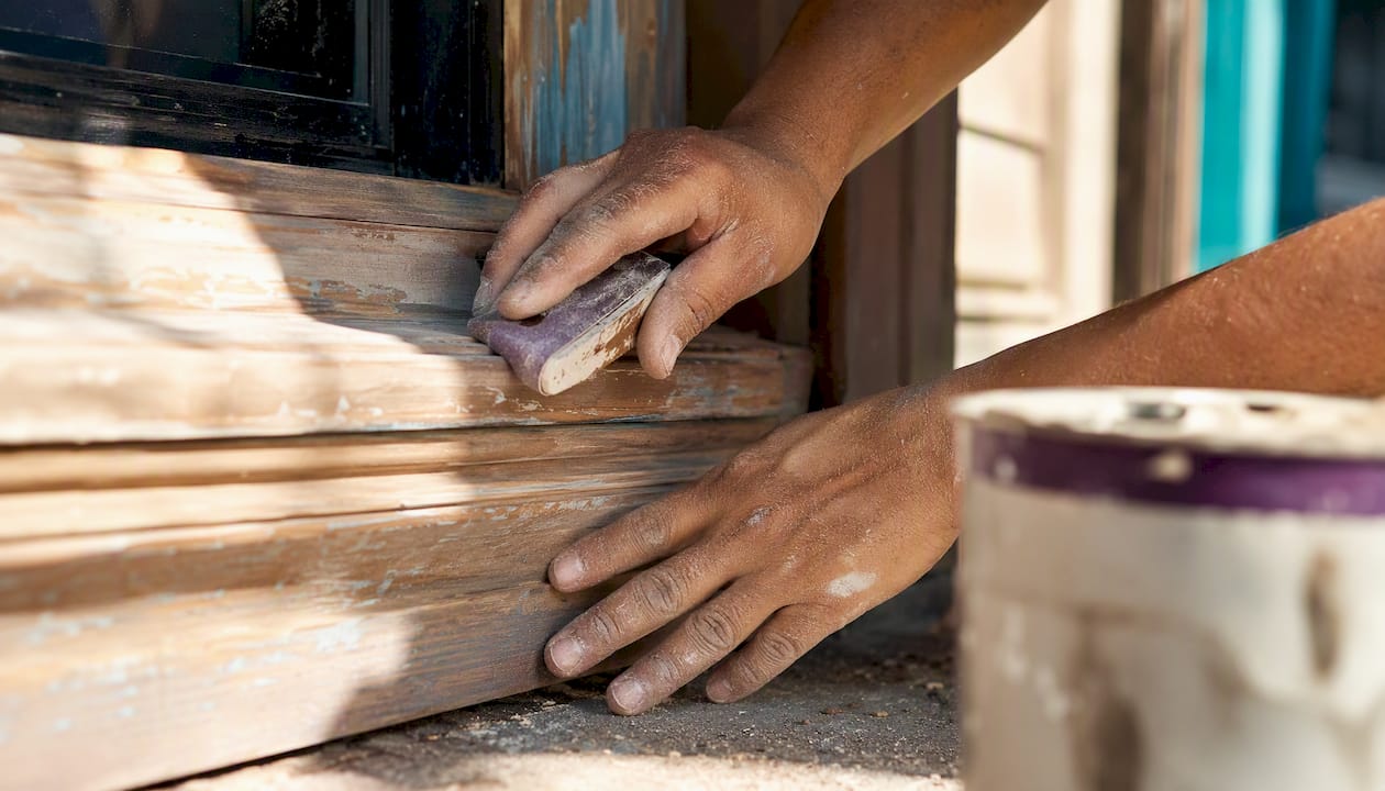 Hands sanding wooden storefront trim