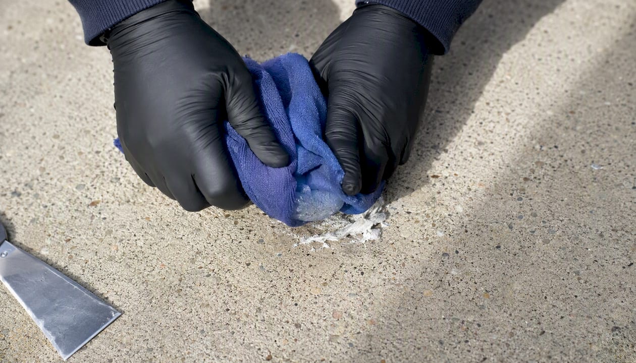 Hands freezing gum stain on sidewalk with ice pack