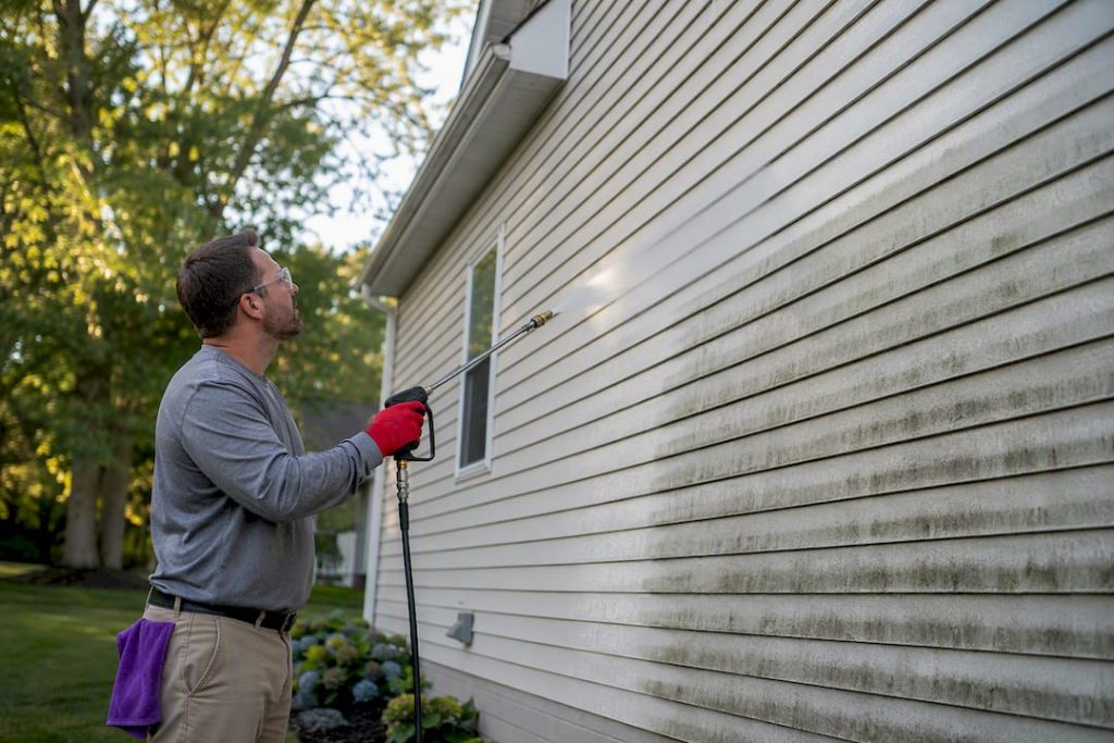 Cleaner applying soft wash to vinyl siding