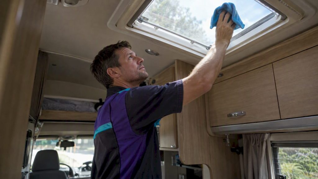 Technician cleaning an RV skylight from inside