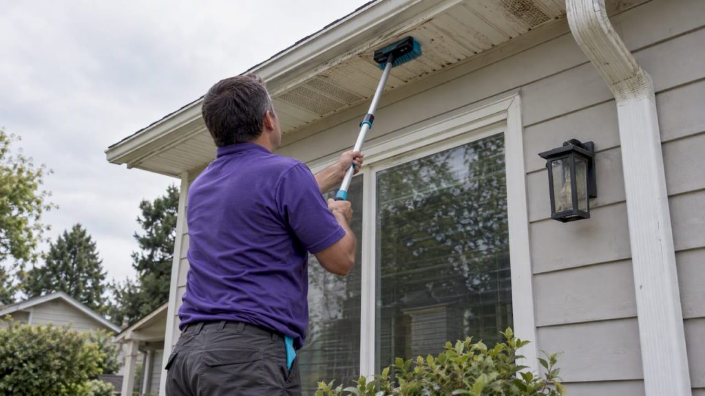 Technician cleaning fascia with an extension pole